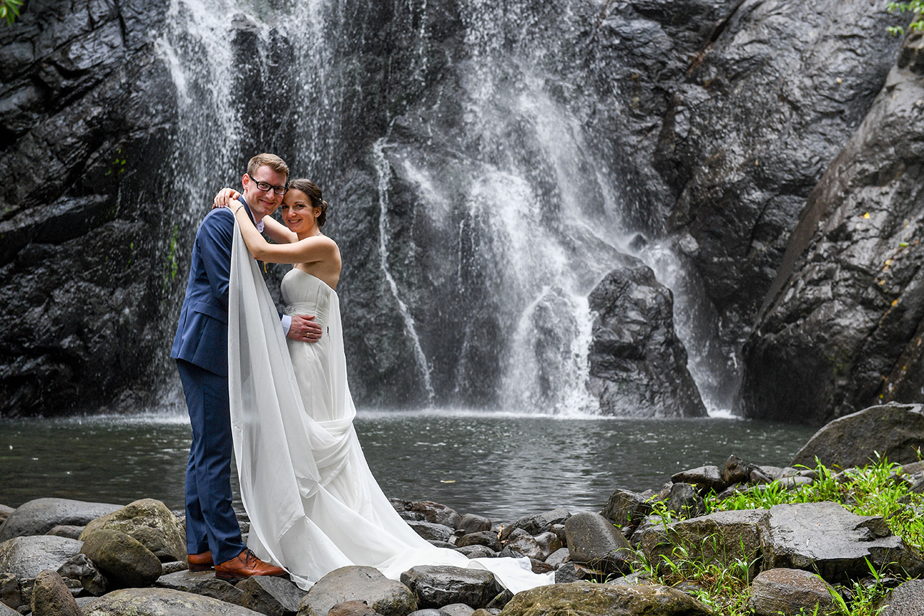 Bride and groom pose in front of waterfall