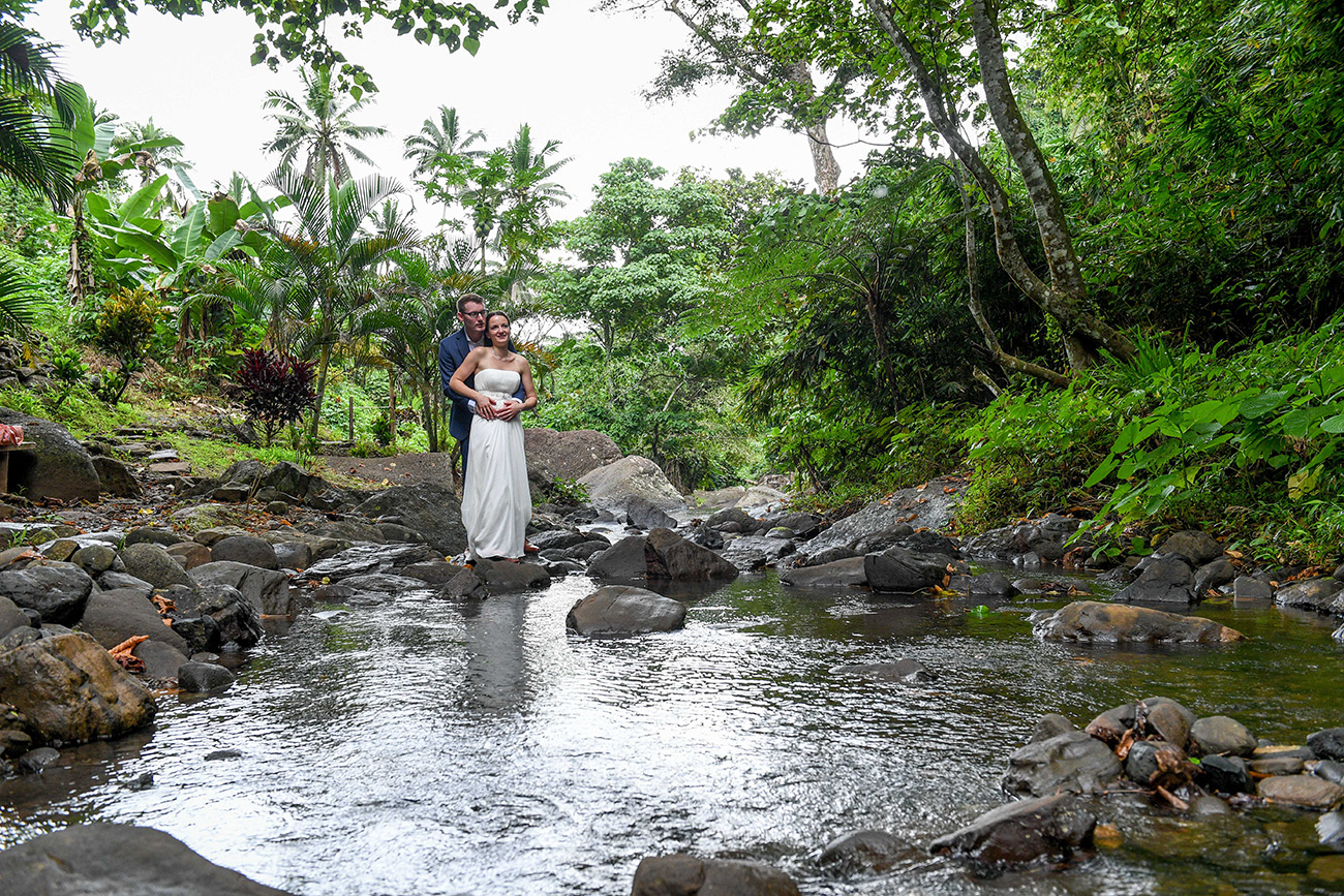 Happily eloped couple hug infront of a small pond in wedding photoshoot