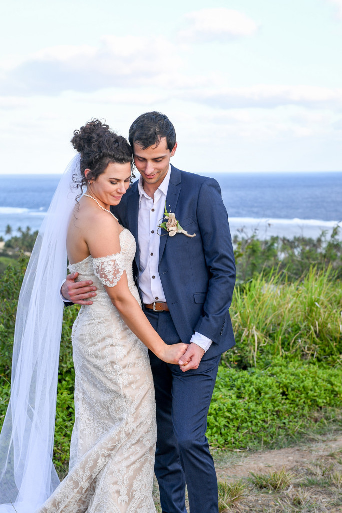 Bride and groom hold hands in Fiji greenery at boho wedding