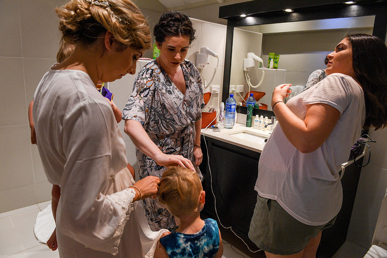 Bridal party watch as the best boy's hair is combed during preparation