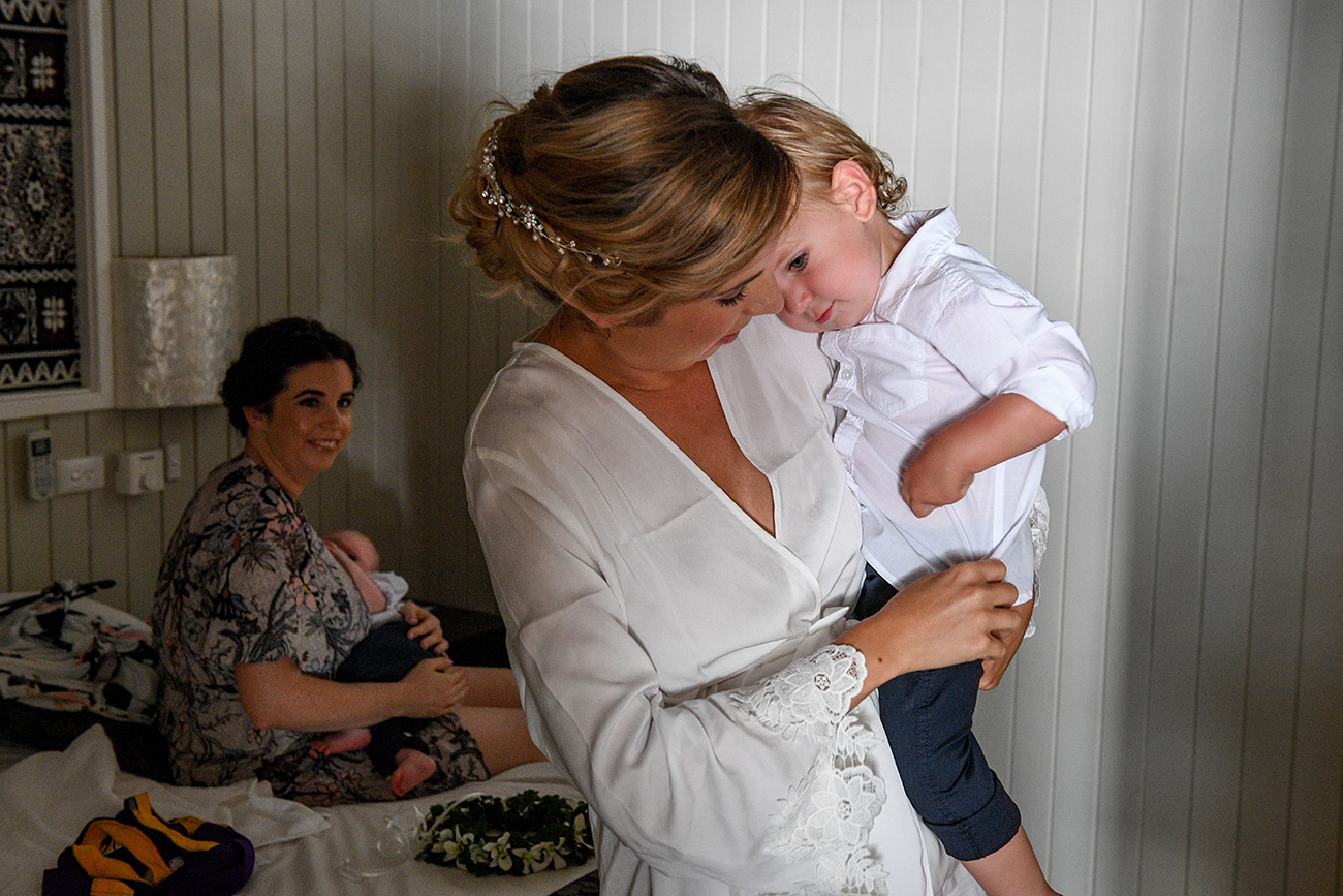 Bride carries her crying son at the wedding preparations