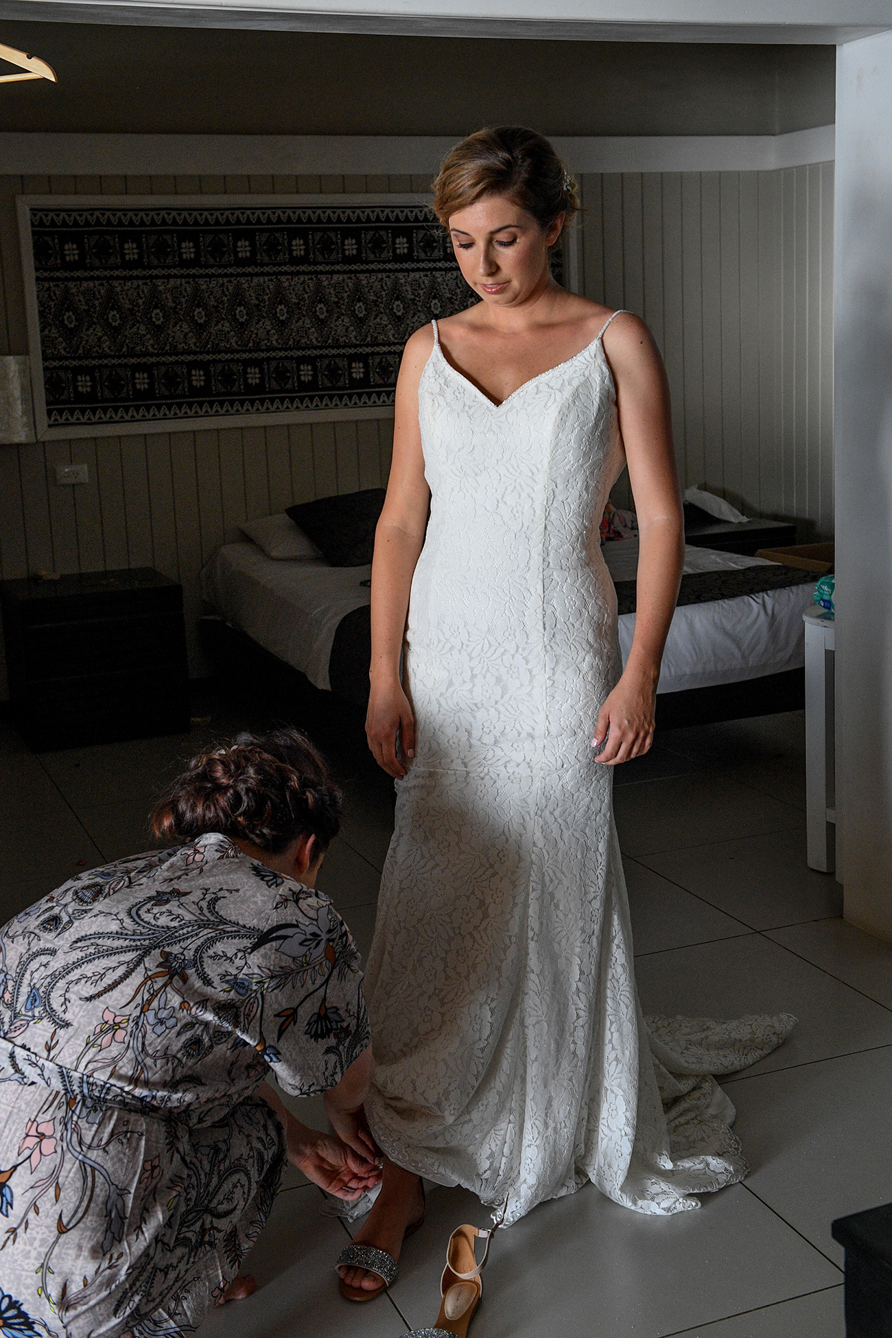 The bride steps into her silver sandals during wedding preparation