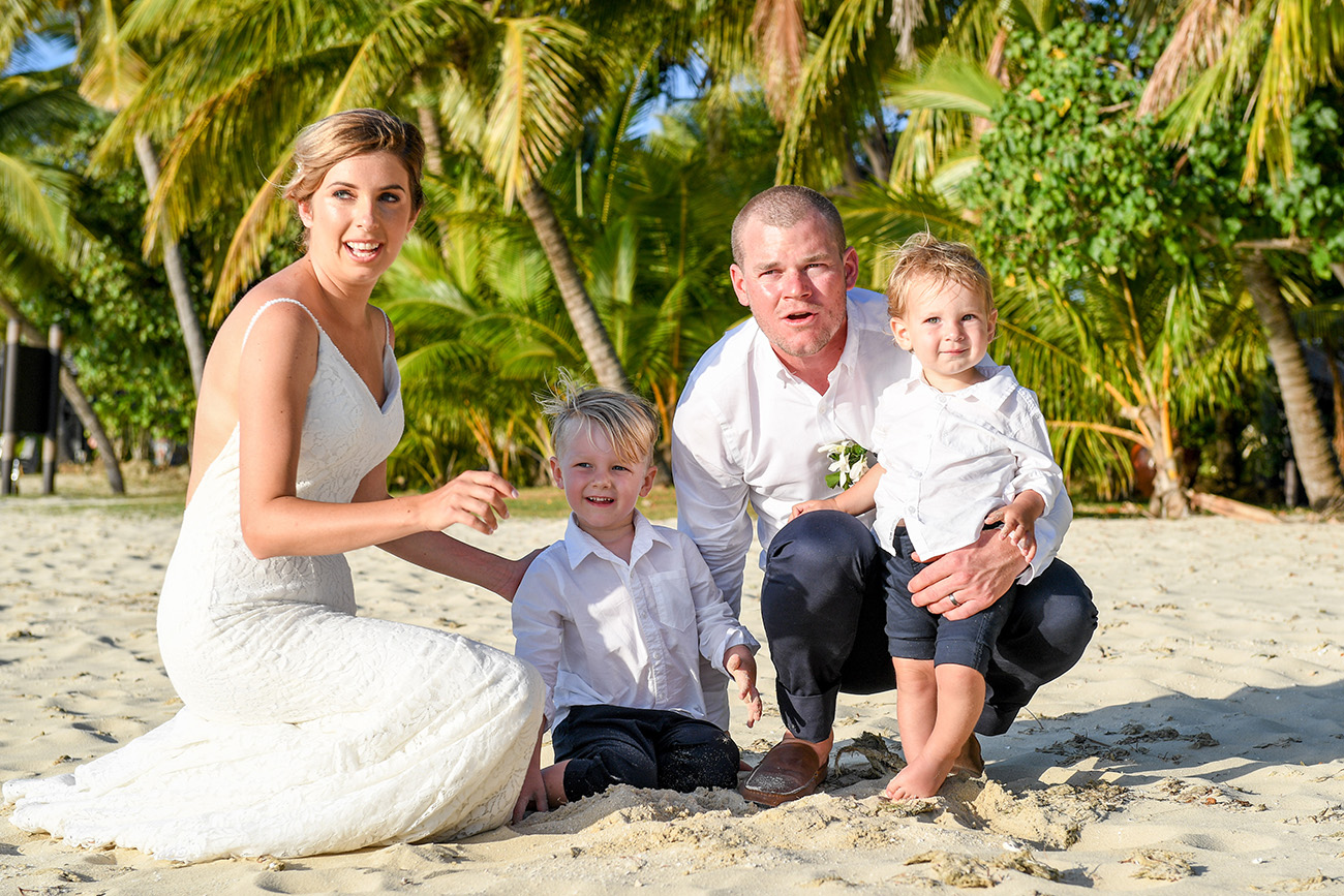 The married couple pose with their children on the Fiji beach