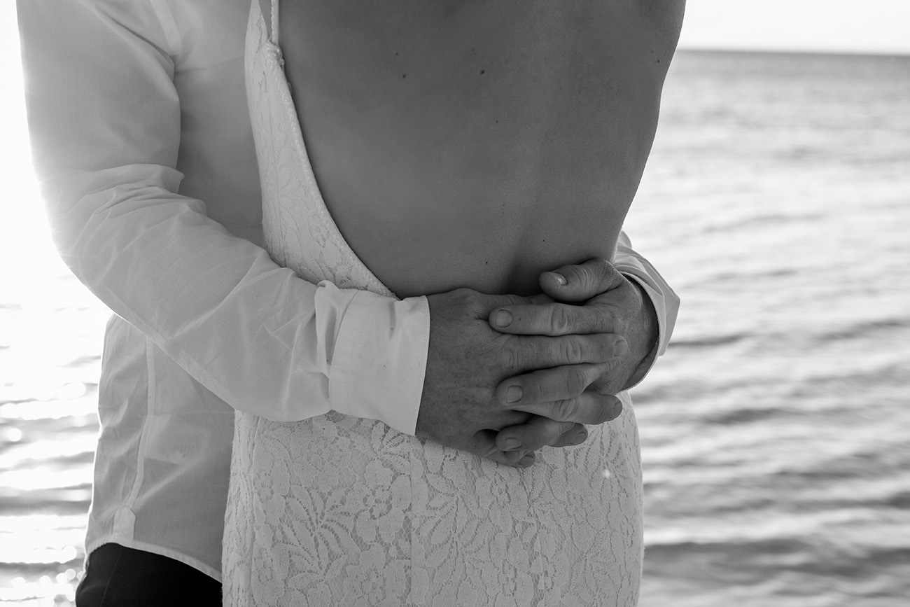 Black and white Closeup of groom hugging bride's bareback