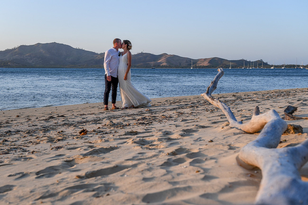 Longshot of Bride and groom kissing against the sea