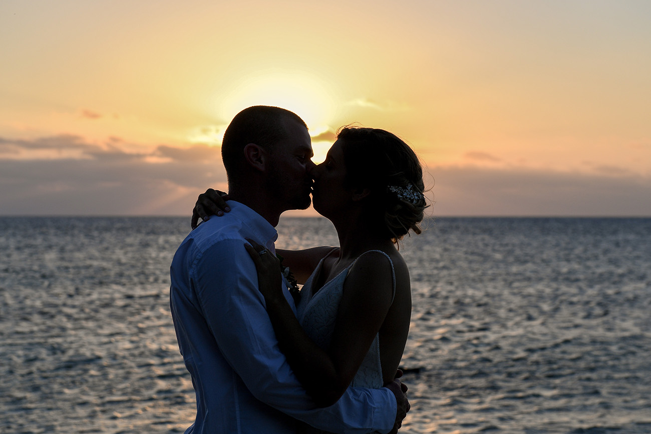 Silhouette of bride and groom kissing against the sunset