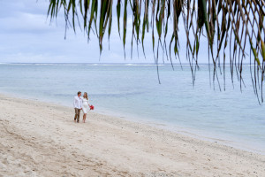 The pregnant bride and groom are walking along the Warwick beach on the coral Coast in Fiji