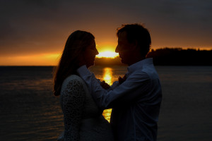Silhouette of the bride and groom by a sunset on fire in Fiji by the beach