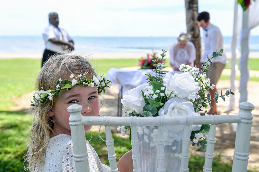 Flowergirl cheekily peeks through chair rifts during wedding ceremony