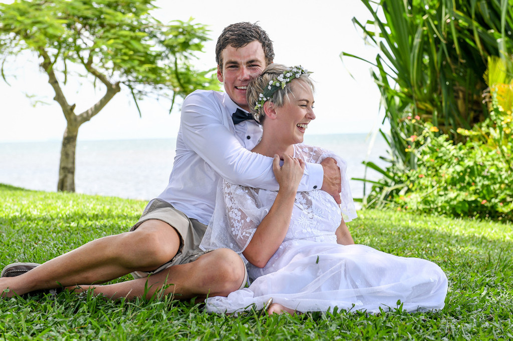 Bride and groom cuddle on manicured lawn of the Hilton hotel in Denarau Fiji