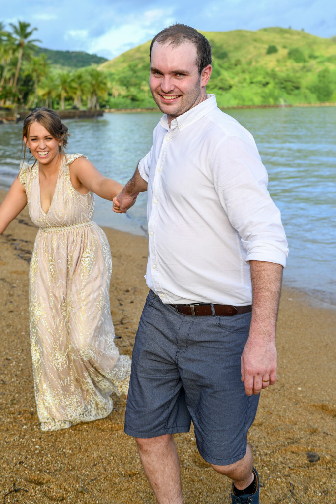 Groom leads his bride along the beach