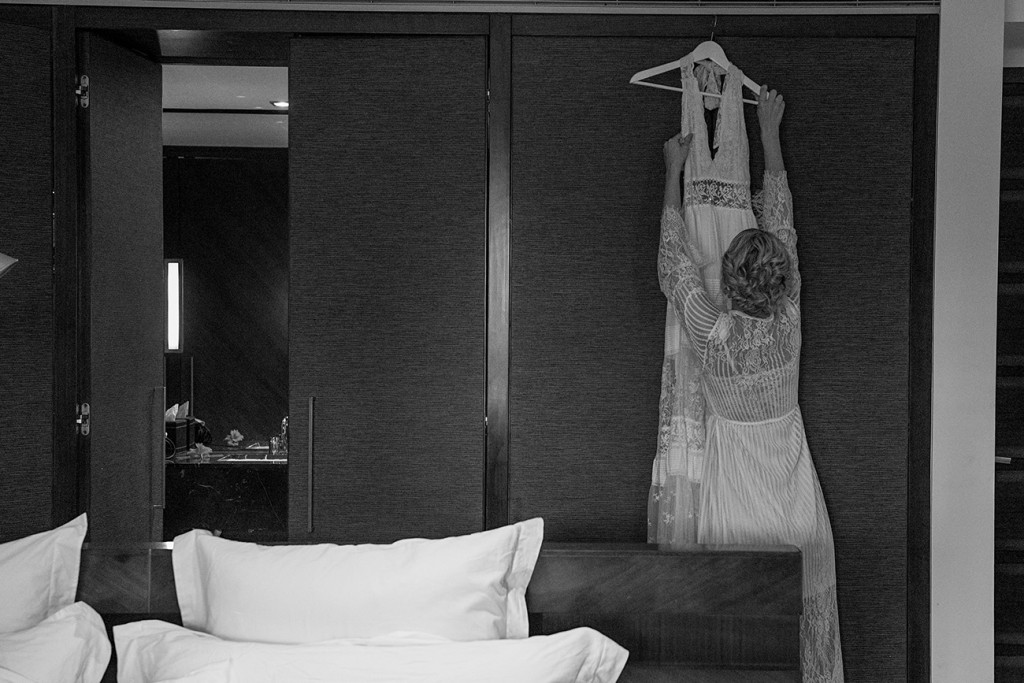 Monochrome photo of bride unhanging her bohemian wedding dress by Spell & The Gypsy