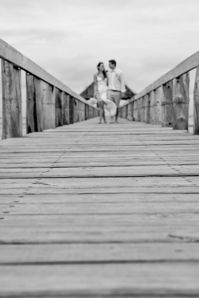 Monochrome picture of the newly married couple strolling hand in hand on the docks
