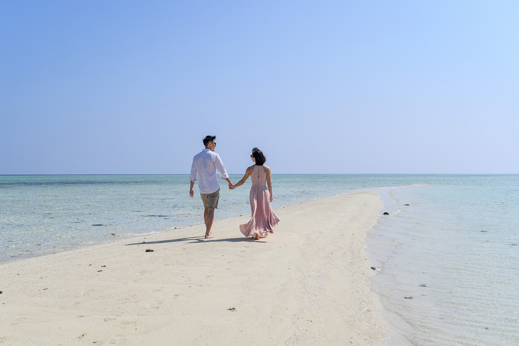 The newly married couple stroll in the reef path on the beach