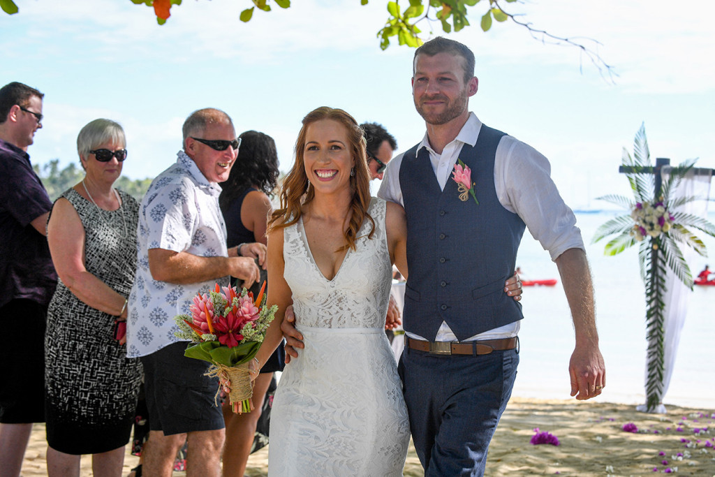 Guests watch as the newly married couple walk down the aisle at their beach wedding