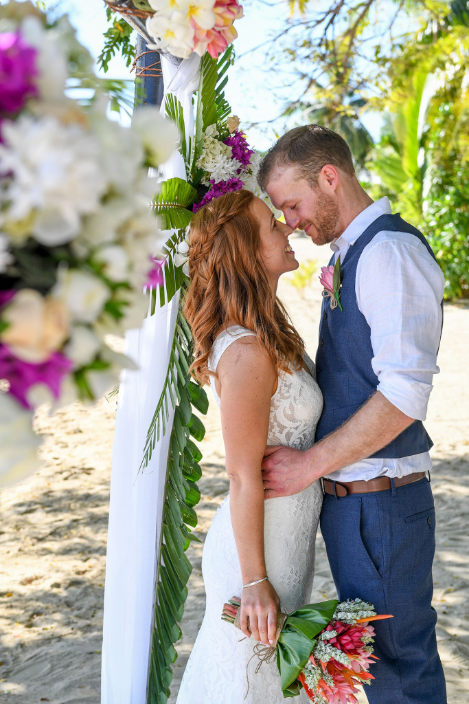 The newly married couple share an up-close and personal moment under the tropical flower altar