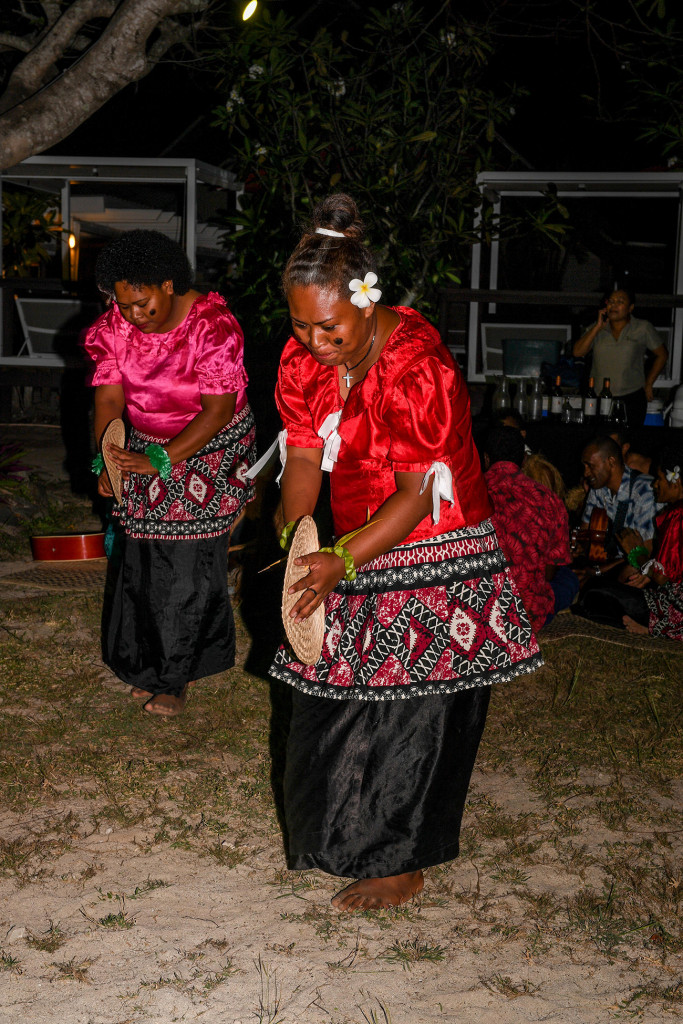 Fiji women dancing traditional Fiji songs with fans on the beach
