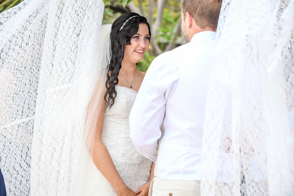 The bride smiles at her groom while at the altar