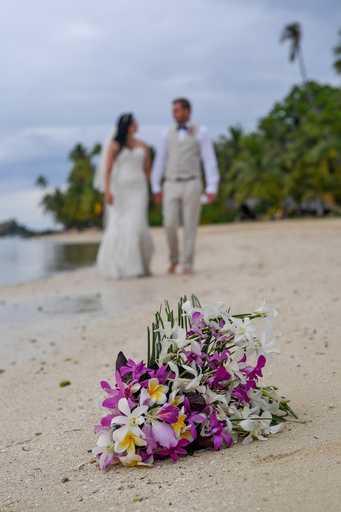 The newly weds pose behind their tropical flower bouquet