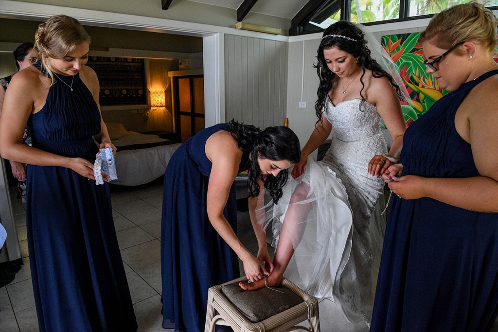 A bridesmaid helps the bride where her wedding sandals