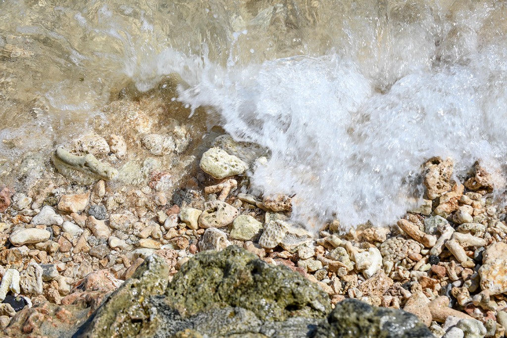 The clear waters at Savasi Fiji wash over the smoothened rocks at Savasi Fiji