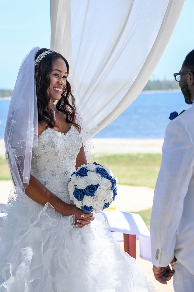 The bride grins at her husband while at the altar at the beach