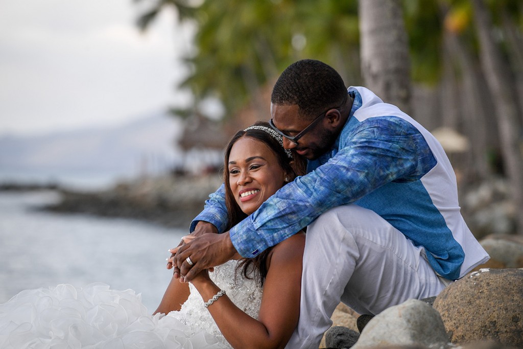 the bride and groom cuddle on the shores of the Pacific ocean