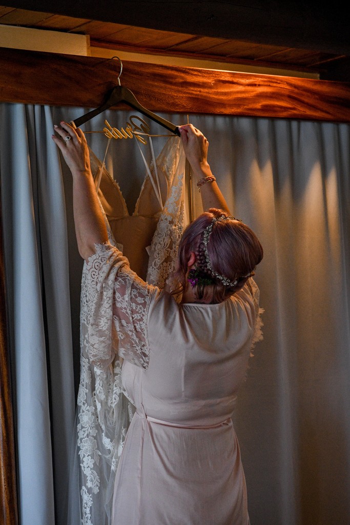The bride lifts her dress off the hanger