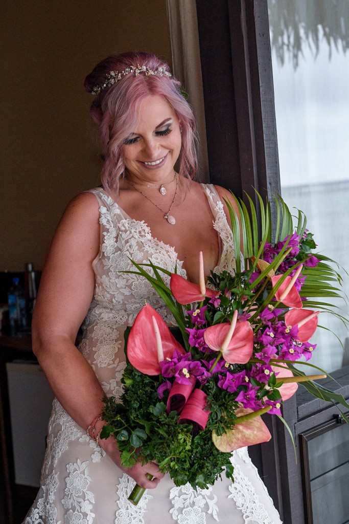 The happy bride poses with her purple and pink flower bouquet