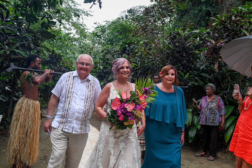 The bride is walked down the aisle by her parents