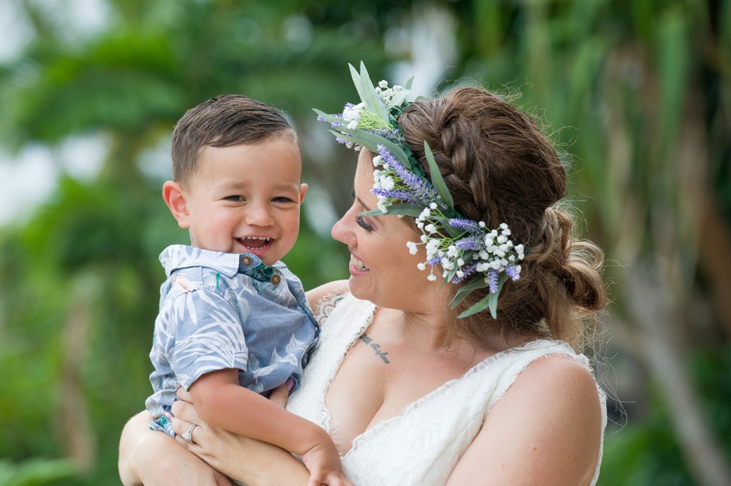 The bride laughs with her son against green palm trees