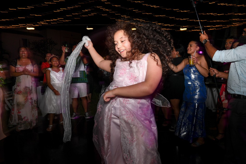 The flower girl dances freely in the under the fairy lights and Fiji night sky at the wedding reception
