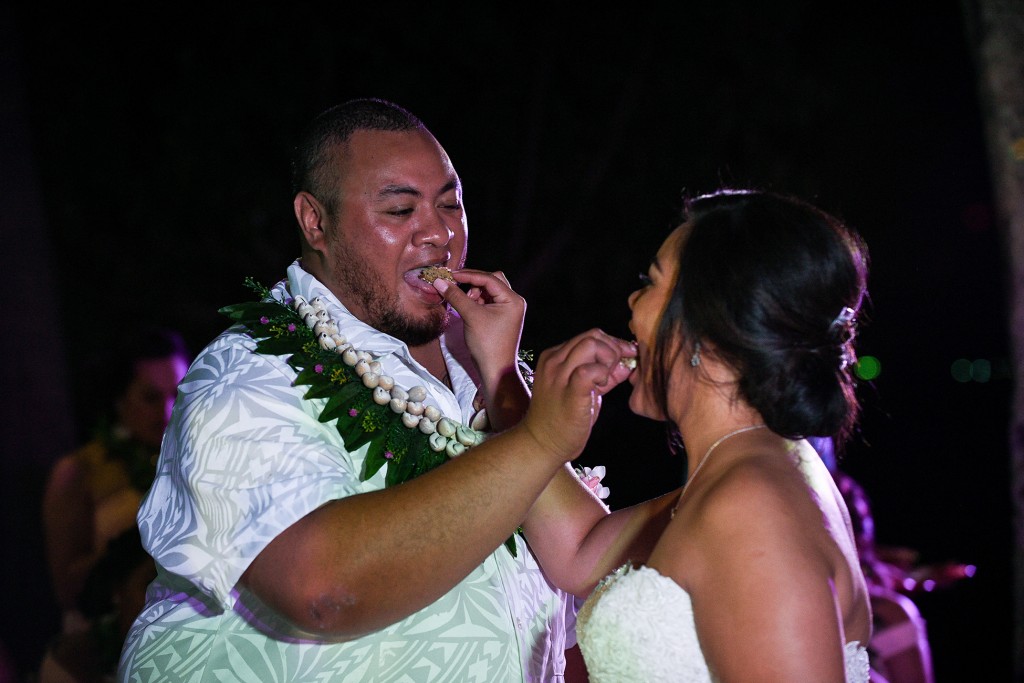 The newly weds feed each other wedding cake under the night sky