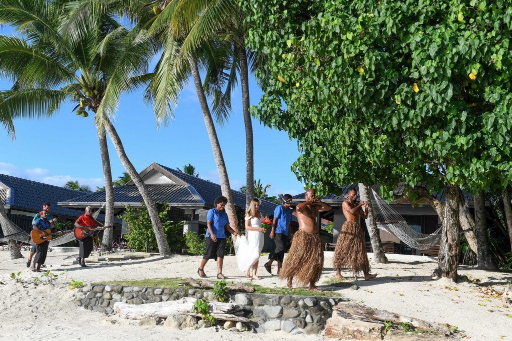 The bride walks down the aisle with a traditional Fiji procession