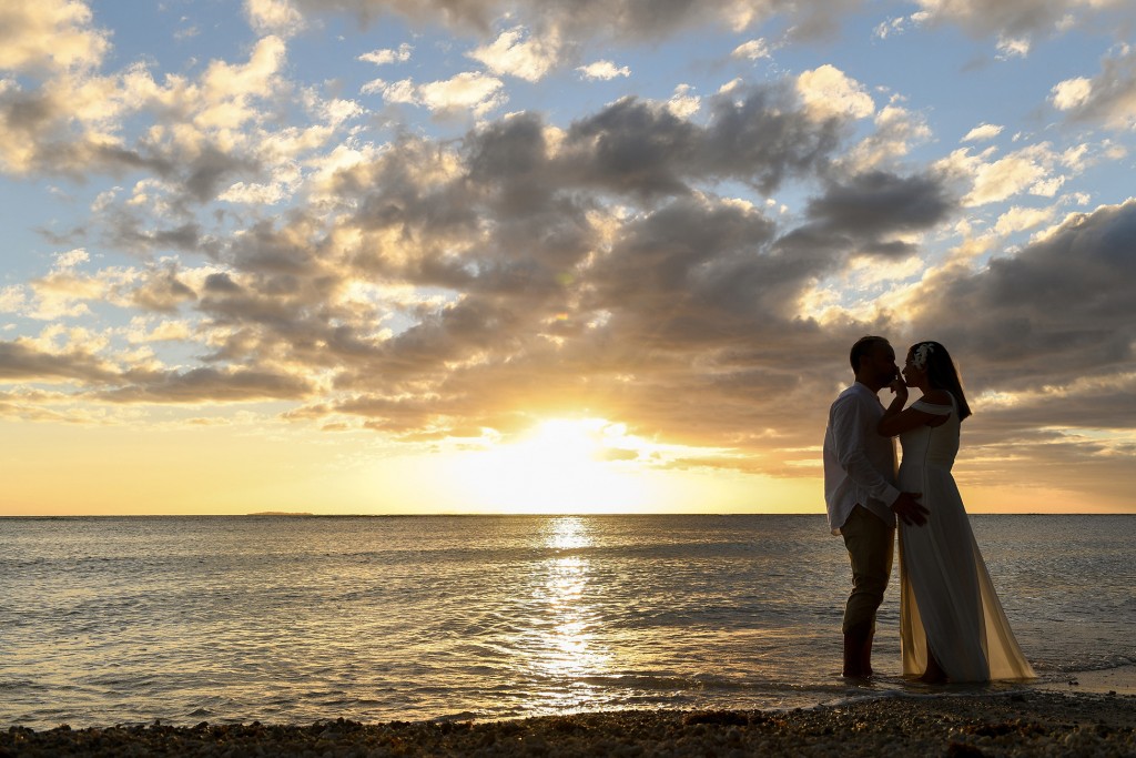 The married couple embrace against the golden Fiji sunset