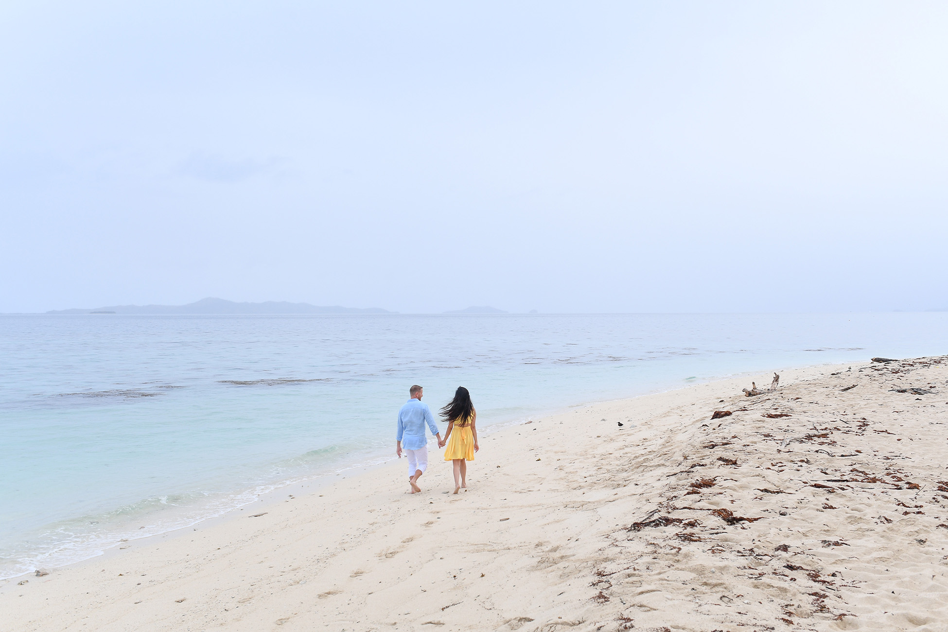 The couple strolls hand in hand on the beige Manunca Fiji beach