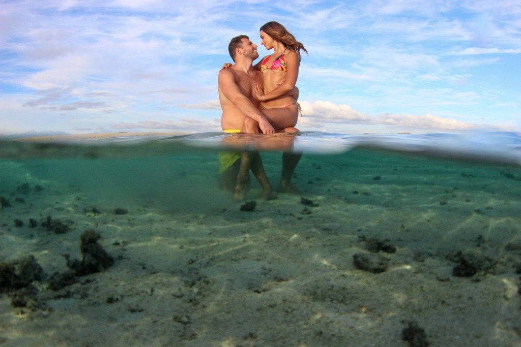 Girlfriend sits on boyfriend's knee in shallow reef of Nadi Fiji