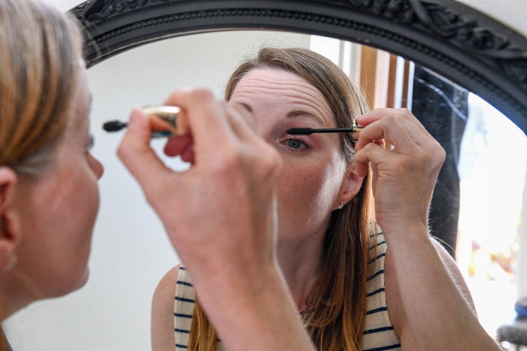 The bride applies her mascara in the mirror