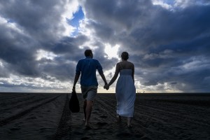 A silhouetted image of the married couple strolling hand in hand