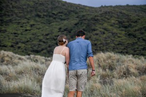 The couple walks towards the rolling green hills of Karekare beach