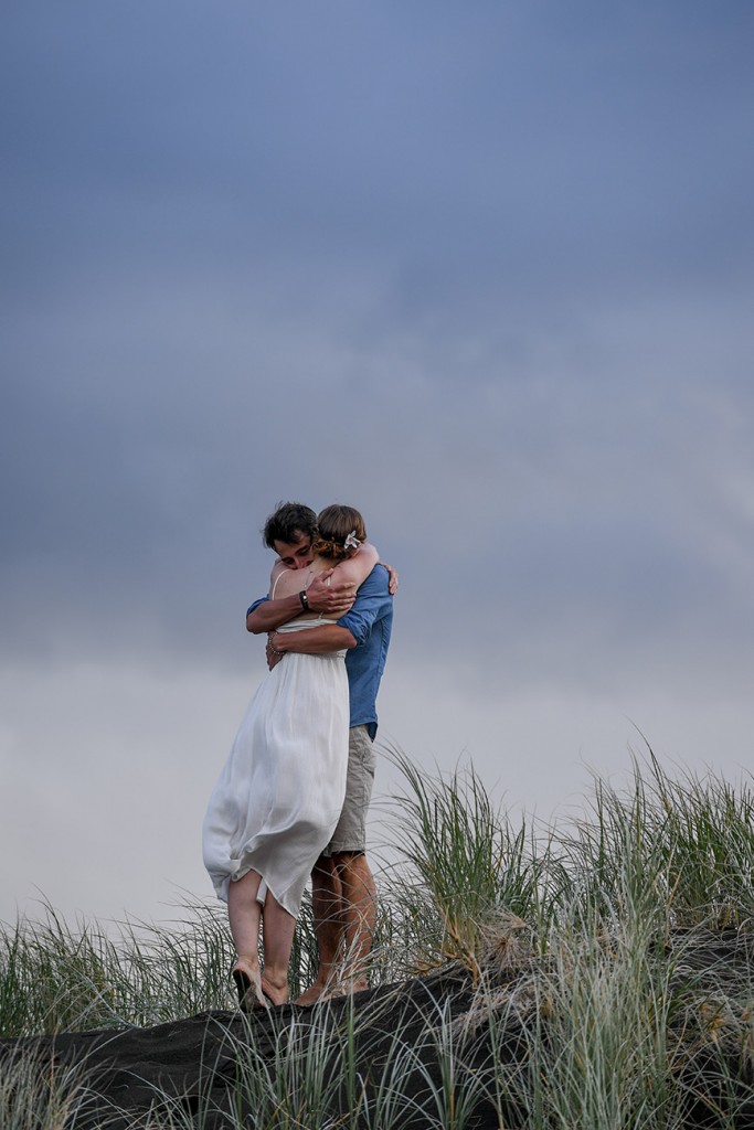 The newly weds hug against heavy grey skies