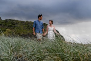 The newly weds walk through patches of grass