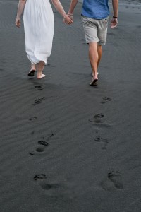 The newly weds leave footprints in the black sand at Karekare
