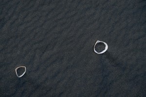 The simple rings rest on Karekare beach black sands
