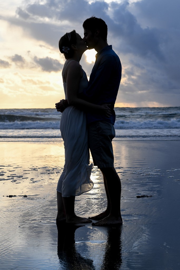 A silhouette of the couple kissing on the black sand beach