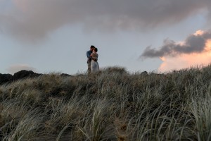 The newly weds hug on a lonely hill at sunset