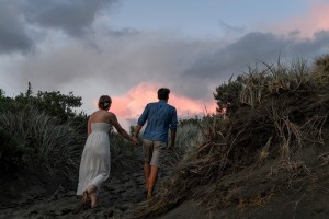 The couple hold hands as they walk over the hills