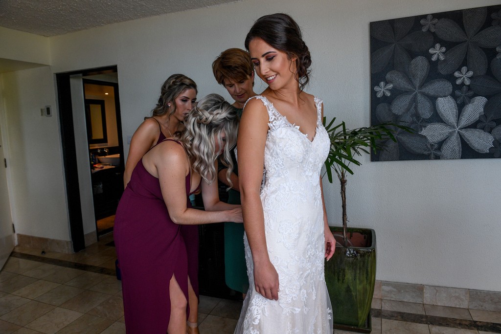 The bride is zipped into her brilliant white lace dress