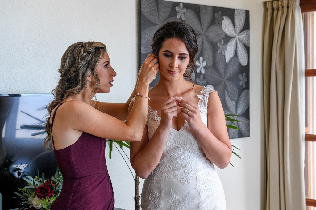 A bridesmaid helps the bride with her earrings