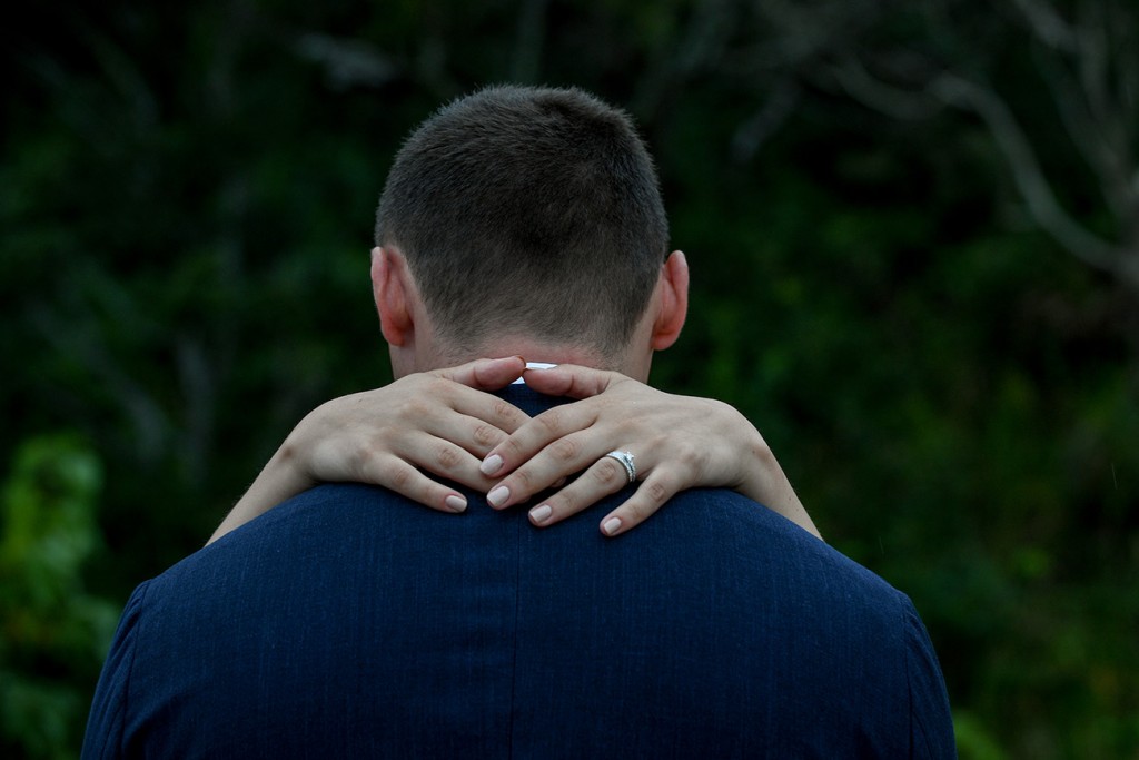 A closeup of the bride's hands over her groom's shoulder